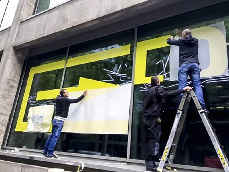 Photo de poseurs d'adhésif sur vitrine à Paris